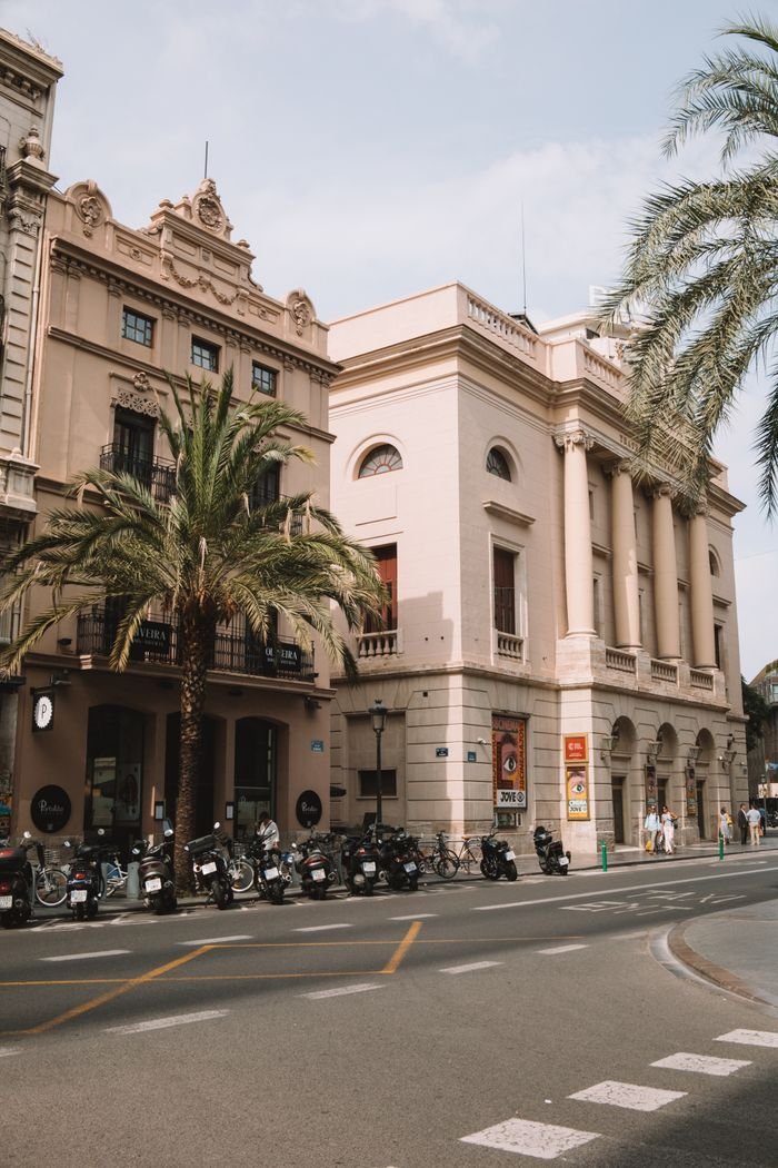 Services Street view of historic buildings and motor scooters in Valencia, Spain on a sunny day.